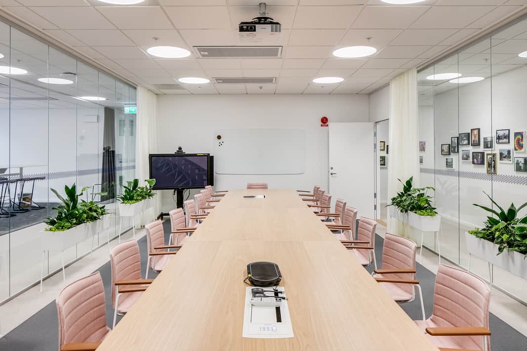 Konferensrum med rosa läderstolar som står runt bordet.