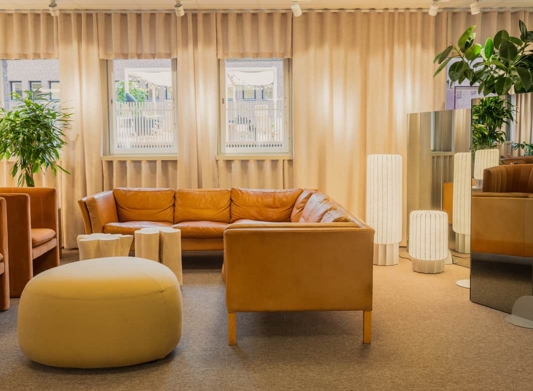 Stor yta inomhus med soffor, reception, människor som sitter vid bord