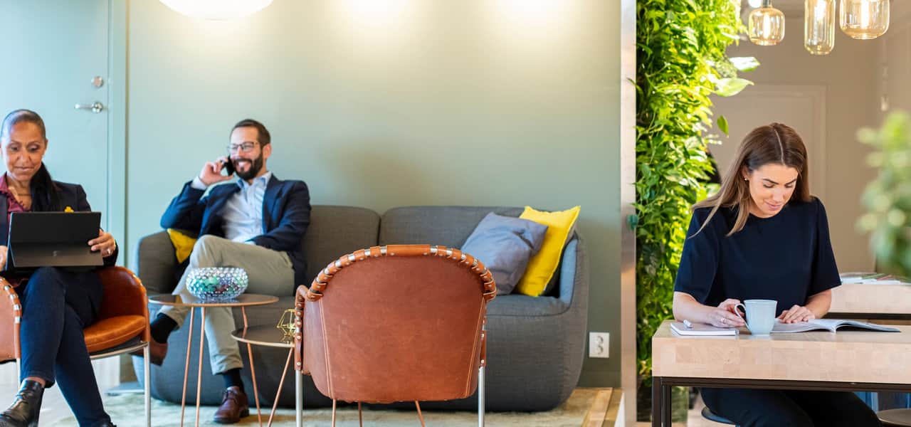 Tre personer i ett öppet kontorslandskap.