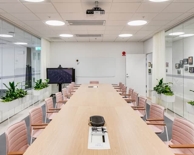 Konferensrum med rosa läderstolar som står runt bordet.