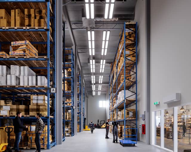 En stor lagerlokal med många hyllor fyllda med lådor.