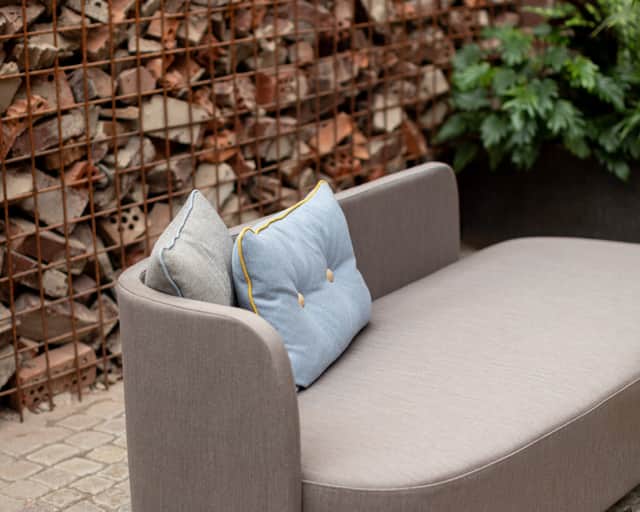 Gabionmur med tegel i sig. Soffa står framför.