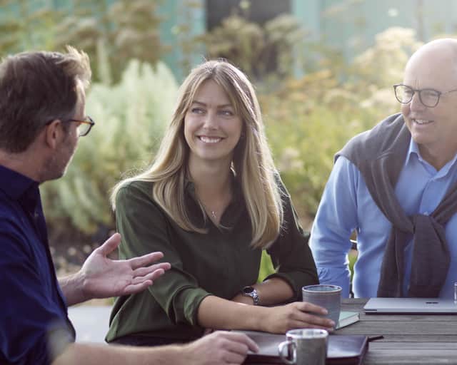 Tre personer kring ett bord utomhus.