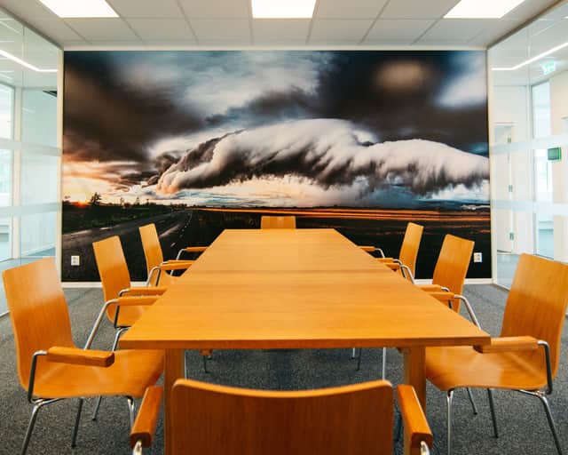 Konferensrum med orangefärgade möbler och fototapet med åskmoln