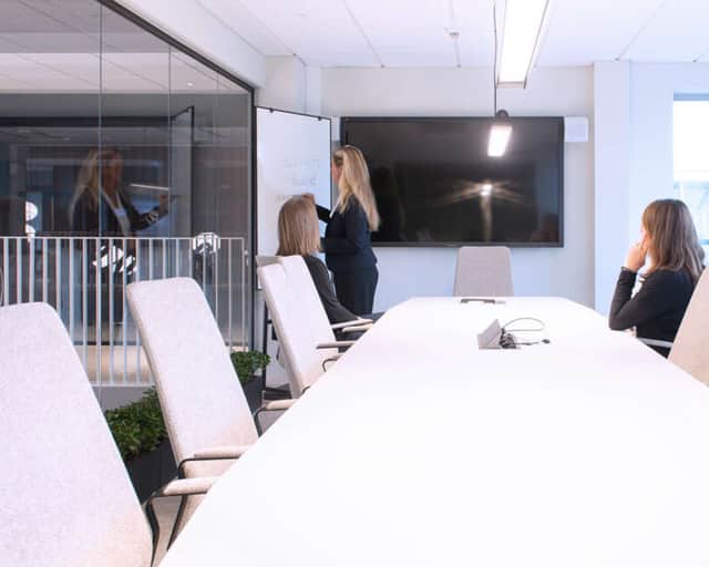 Tre personer i ett mötesrum.