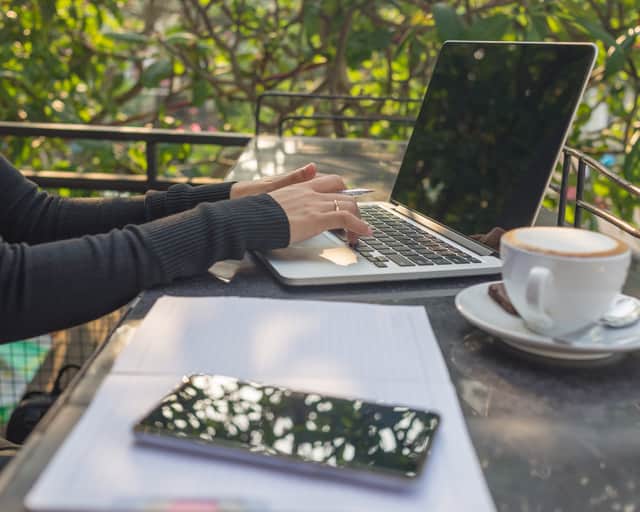 Person med dator vid bord utomhus.