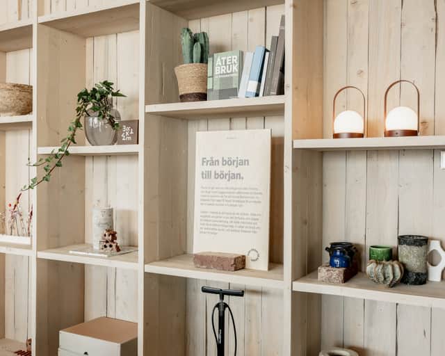 Bokhylla i ljust trä med olika föremål i.