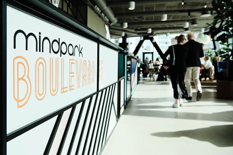 En skylt med företagsnamn i förgrunden, suddiga människor i bakgrunden.