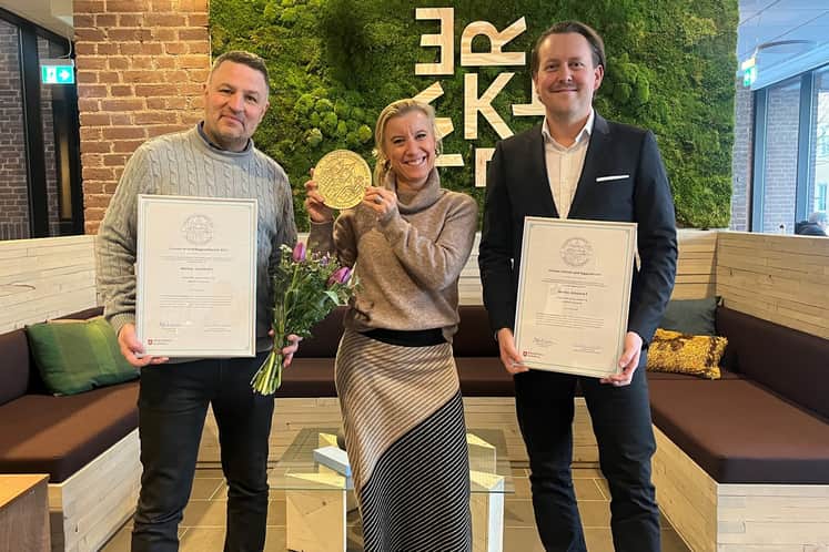 Tre anställda på Castellum som håller upp blommor, diplom och plakett