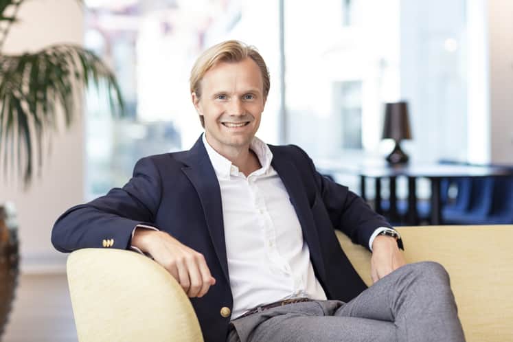 En man i kostym sitter i en soffa.