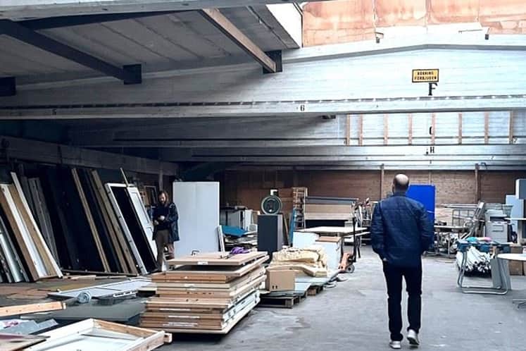 Två personer i ett utrymme med gamla fönster.