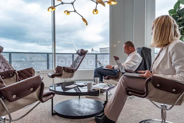 Två personer i fåtöljer vid ett fönster.