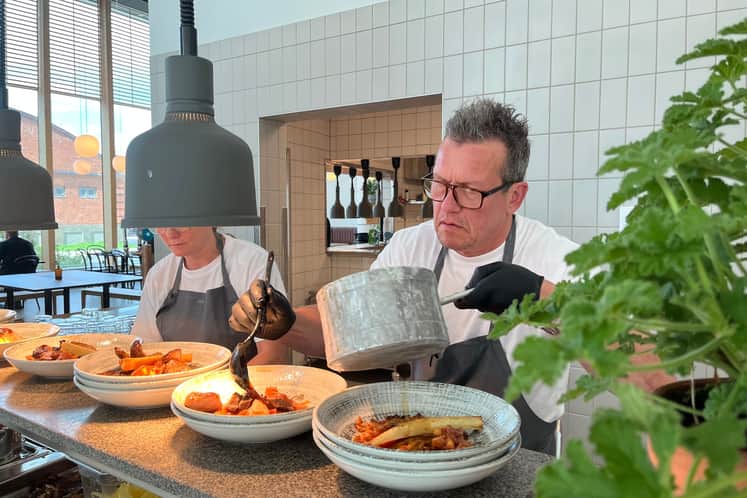 I restaurang, en man häller upp mat på en tallrik 