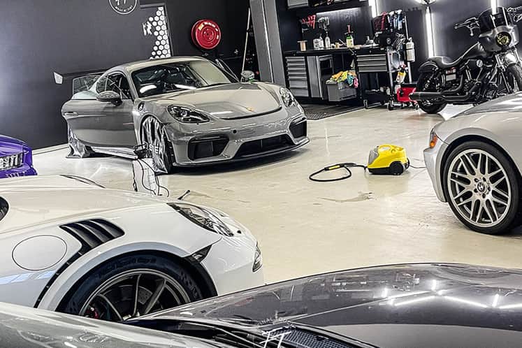 Bilar och motorcykel i en verkstad.