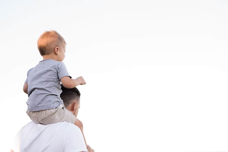 Förälder med barn på axlarna.