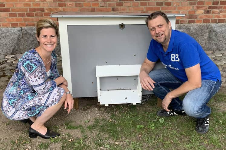 Två personer framför en bikupa.