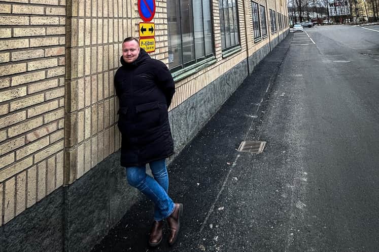 Person lutar sig mot byggnad på gatan.