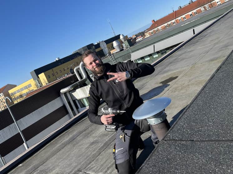 Andreas på ett tak med en skruvdragare i handen