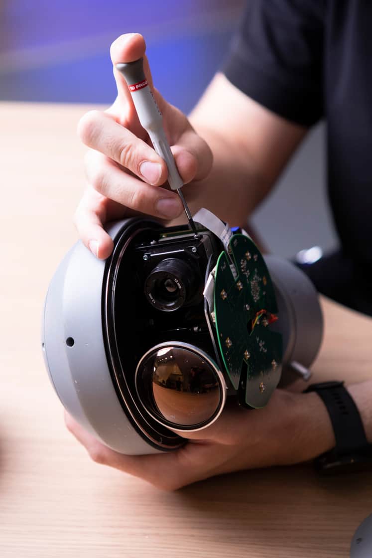 Rund kamera som en person skruvar på med en skruvmejsel