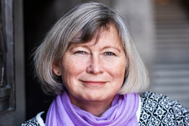 Leende senior kvinna med grå page, lila sjal och svartvit tröja