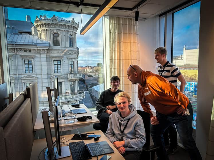 En grupp människor står runt ett skrivbord.