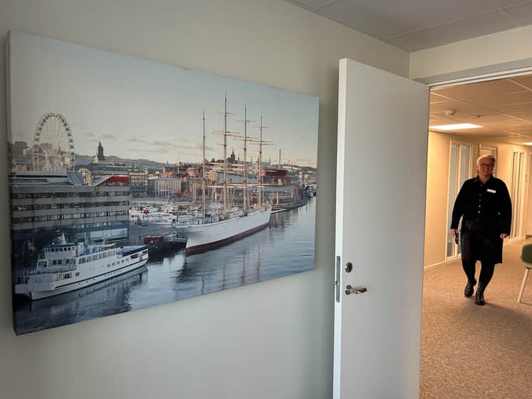 En tavla intill en öppen dörr som visar en person gåendes i en korridor