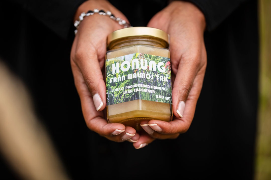 N&auml;rbild p&aring; h&auml;nder som h&aring;ller i en honungsburk.