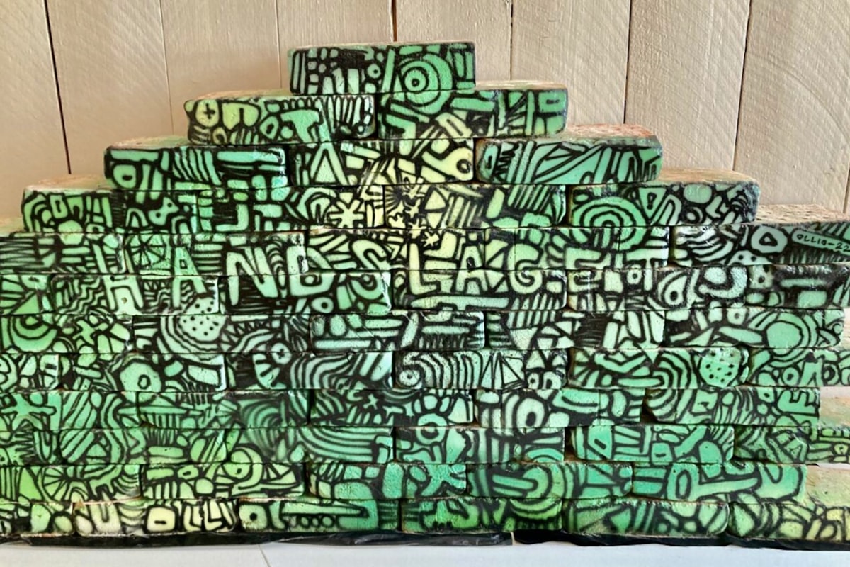 Gr&ouml;nm&aring;lade tegelstenar med texten Handslaget i mitten.