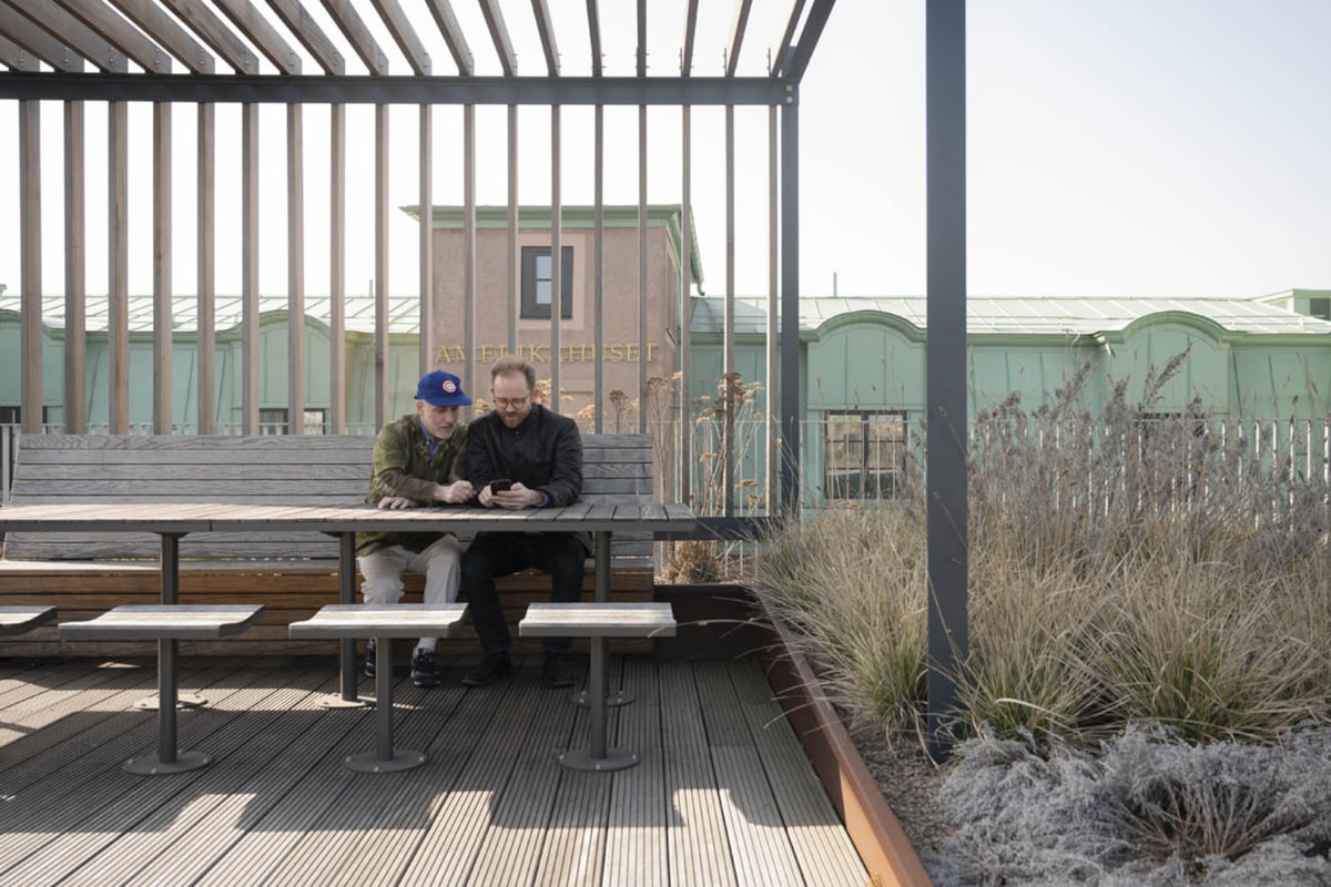 Tv&aring; personer sitter vid ett bord p&aring; en takterrass.