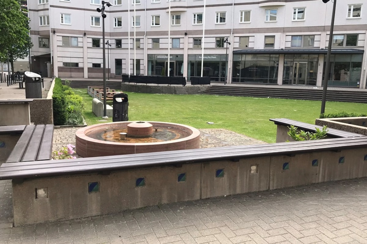 Innerg&aring;rd med font&auml;n och stenb&auml;nkar.