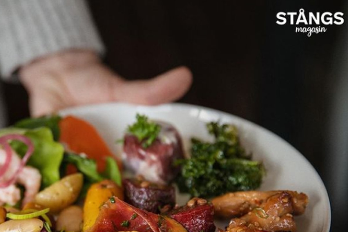 Hand som h&aring;ller i en tallrik med mat.