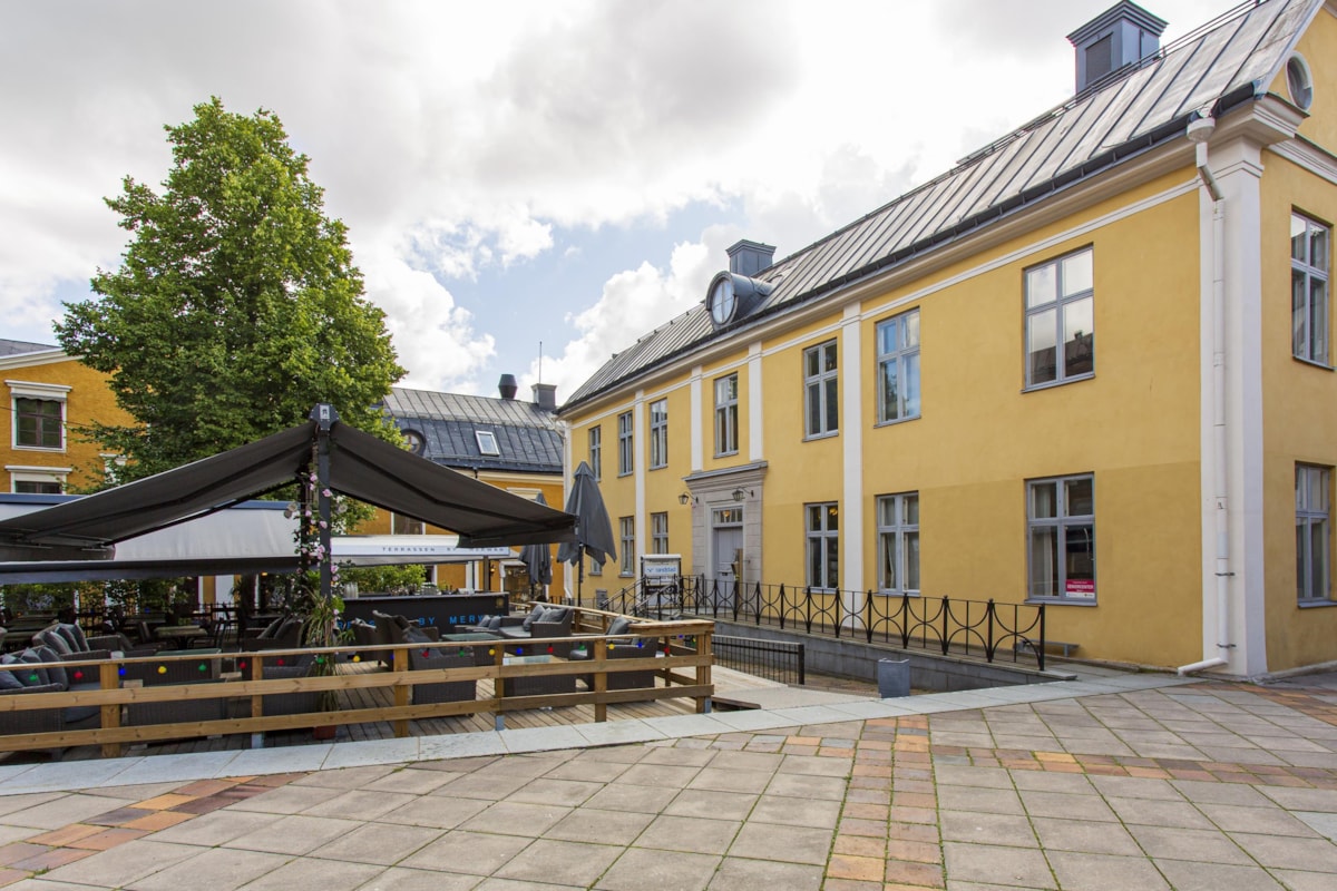 Exteri&ouml;rbild av Gula huset med en uteservering framf&ouml;r.