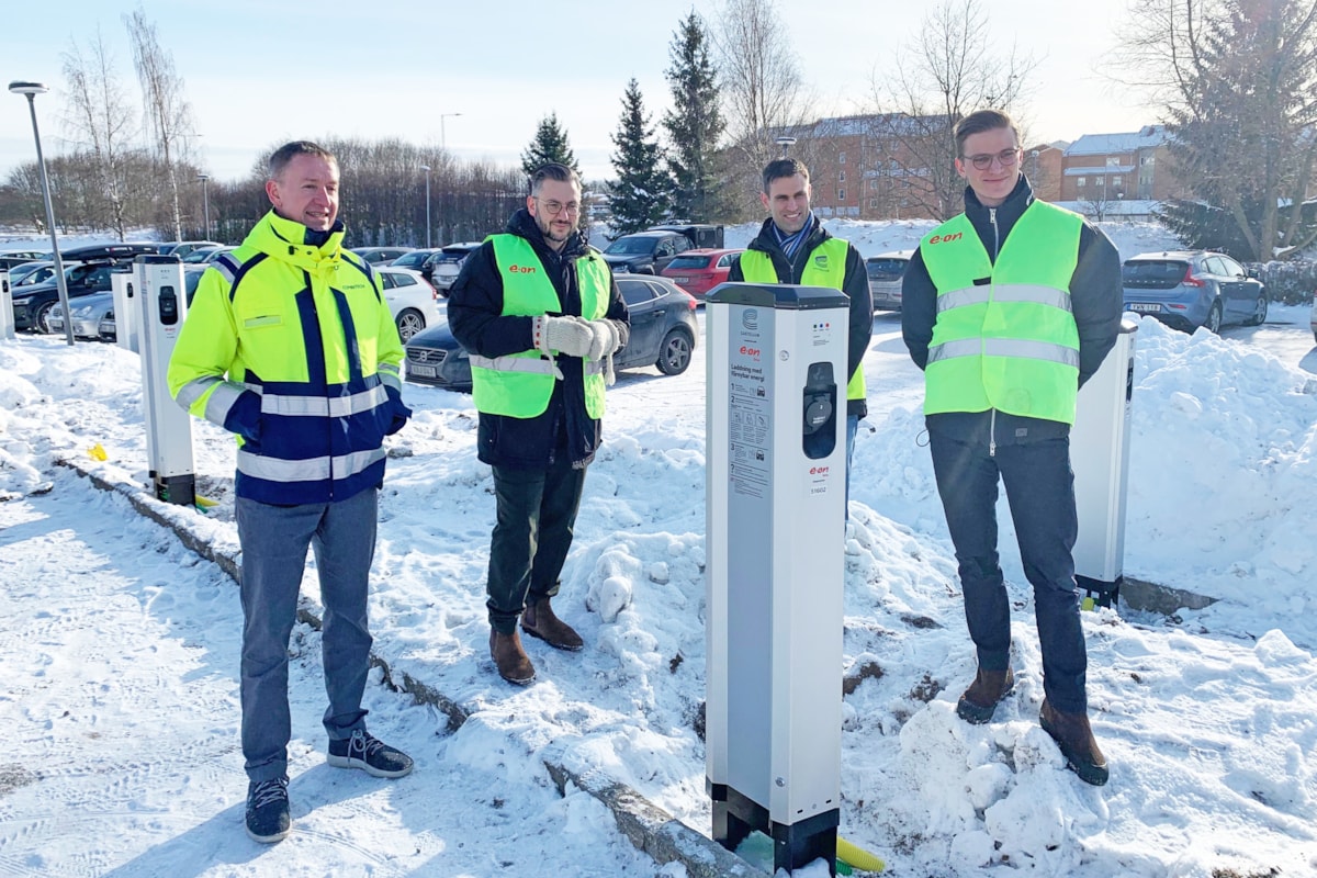 Fyra personer st&aring;r vid en laddstolpe i sn&ouml;.
