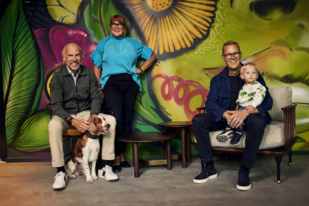 Fyra personer och en hund framf&ouml;r en f&auml;rgglad v&auml;gg.