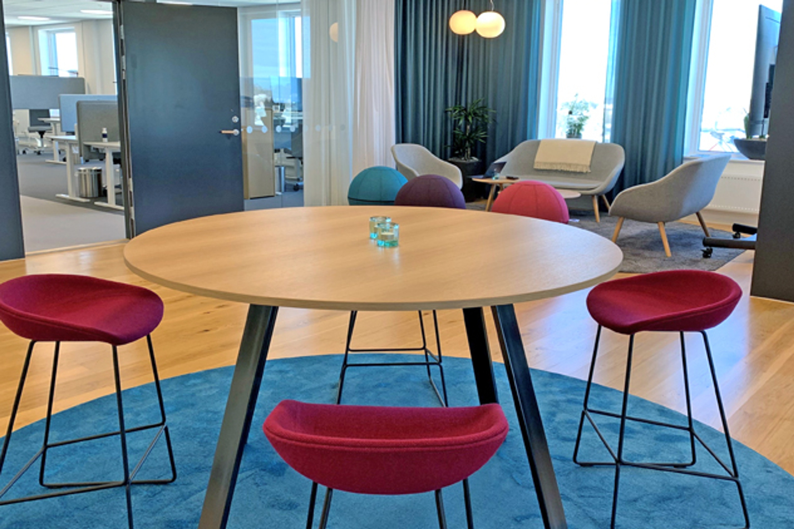 Ett runt bord med r&ouml;da stolar.