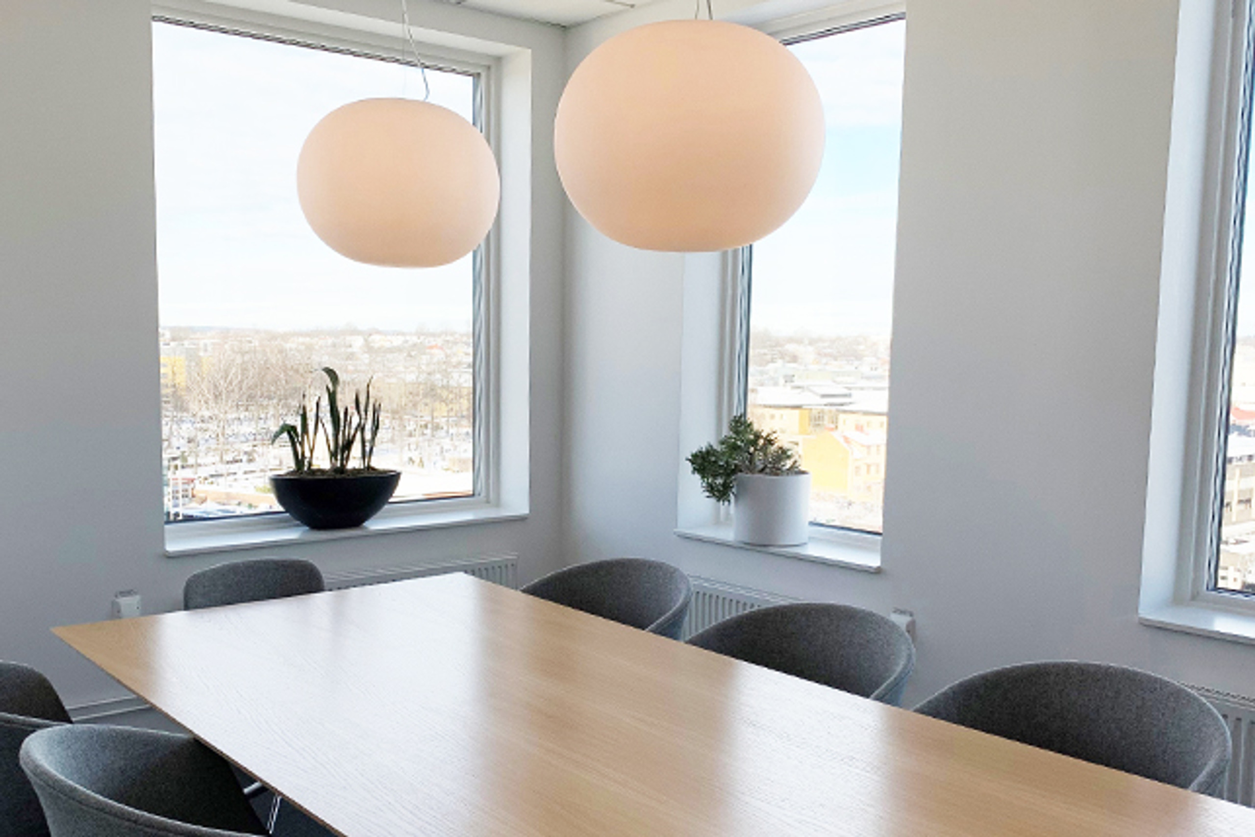 M&ouml;tesrum med l&aring;ngt bord och runda lampor.